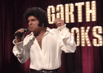 Man Singing Into Microphone With Garth Brooks Sign GIF