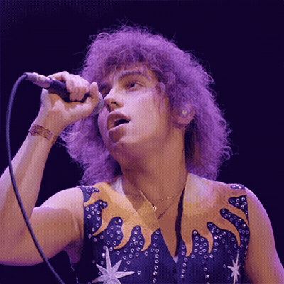Man Singing Into Microphone With Star Vest GIF