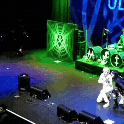 Man Singing On Stage With Microphone And Drum Set GIF
