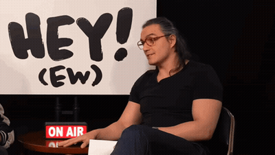 Man Sits At Table In Front Of Sign Saying Hey (Ew) GIF