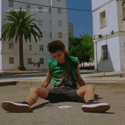 Man Sits On Gound Under Hot Sun GIF