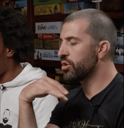 Man Sitting At Board Game Shelf With Scrabble GIF