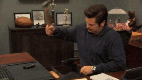 Man Sitting At Desk Holding Hammer GIF