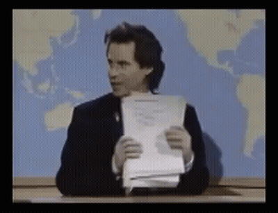 Man Sitting At Desk Holding Paper GIF