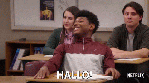 Man Sitting At Desk In Classroom Saying Hallo GIF