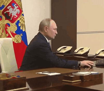 Man Sitting At Desk In Front Of Flag GIF
