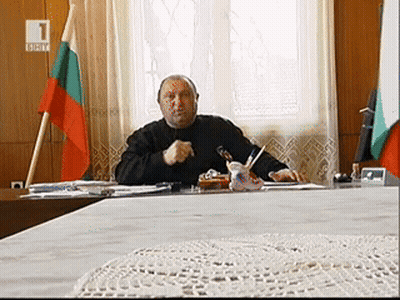 Man Sitting At Desk In Front Of Flag With Number 1 GIF