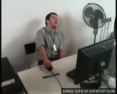 Man Sitting At Desk With Computer And Fan GIF
