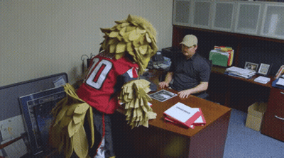 Man Sitting At Desk With Mascot In Number 10 Jersey GIF
