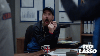 Man Sitting At Desk With Ted Lasso Logo GIF