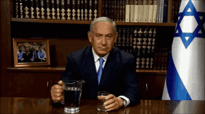 Man Sitting At Desk With Water Pitcher And Flag GIF