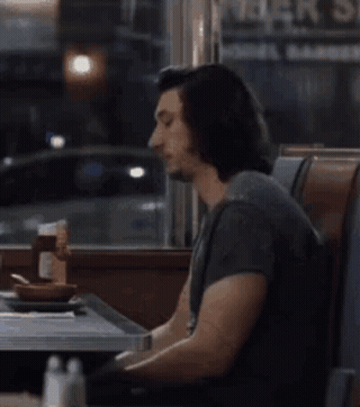 Man Sitting At Diner Table Looking At Cell Phone GIF