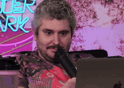Man Sitting At Laptop With Microphone And After Park Neon Sign GIF