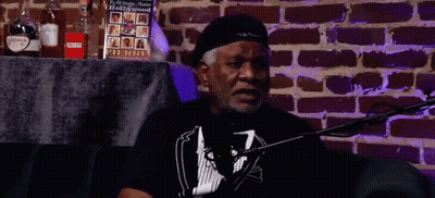 Man Sitting At Microphone By Brick Wall GIF