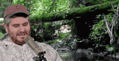 Man Sitting At Microphone In Forest GIF