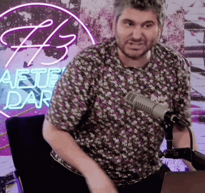 Man Sitting At Microphone In Front Of Aete Dar Neon Sign GIF