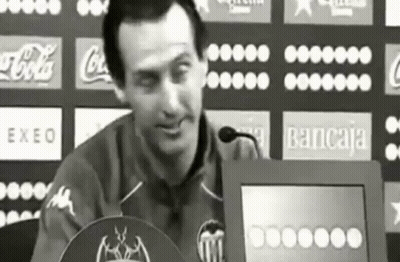 Man Sitting At Podium With Coca-Cola Bancaja Logos GIF