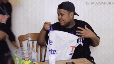 Man Sitting At Table Holding Bag Saying T GIF
