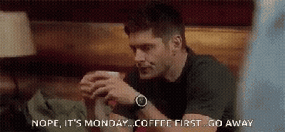 Man Sitting At Table Holding Coffee Talking To Another Man GIF