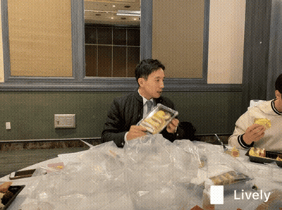 Man Sitting At Table Holding Food Package Saying Lively GIF