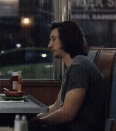 Man Sitting At Table In Front Of Bar Sign GIF