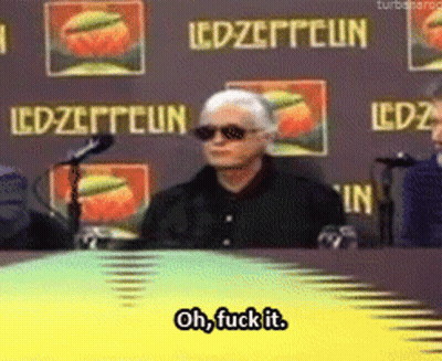 Man Sitting At Table In Front Of Led Zeppelin Sign GIF