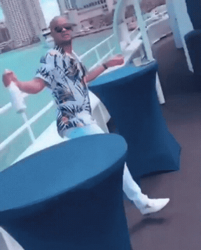 Man Sitting At Table With Arms Outstretched By Water GIF