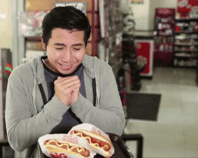 Man Sitting At Table With Big Hot Dogs GIF