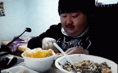 Man Sitting At Table With Bowls Of Food And Spoon GIF