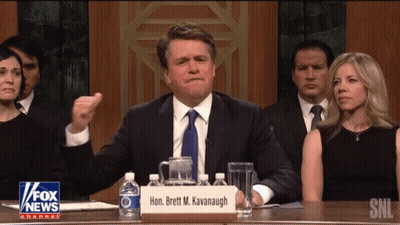 Man Sitting At Table With Brett M. Kavanagh Sign GIF