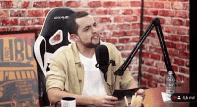 Man Sitting At Table With Microphone GIF