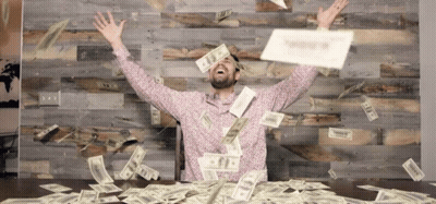 Man Sitting At Table With Money Falling From Sky GIF