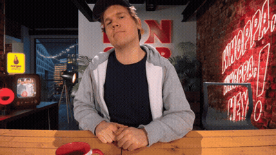 Man Sitting At Table With Neon NN Sign GIF
