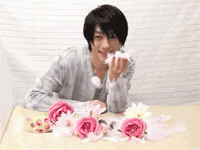 Man Sitting At Table With Pink Flowers GIF