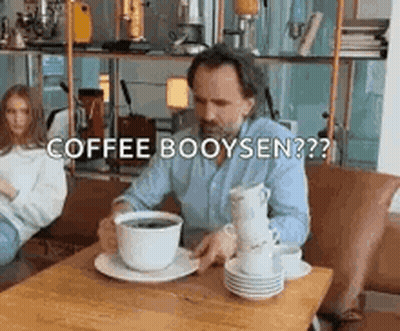 Man Sitting At Table With Stack Of Coffee Cups GIF