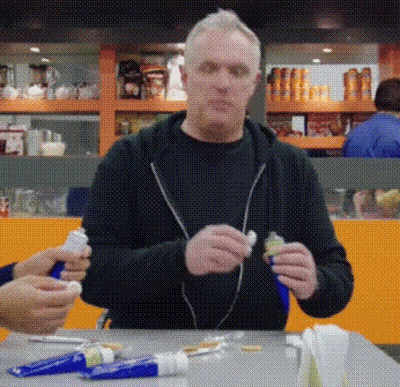 Man Sitting At Table With Toothpaste Tubes GIF