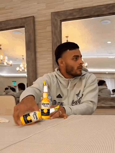 Man Sitting at Table with Two Corona Bottles