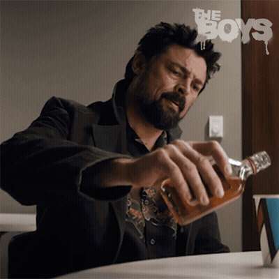 Man Sitting At Table With Whiskey Bottle In Front Of The Boys Sign GIF