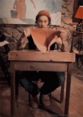 Man Sitting At Wooden Table Holding Paper GIF