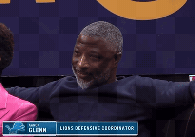 Man Sitting By Aaron Glenn Lions Defensive Coordinator Sign GIF