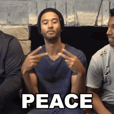 Man Sitting By Fireplace Making Peace Sign GIF
