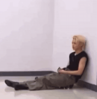 Man Sitting Cross Legged Against Wall GIF
