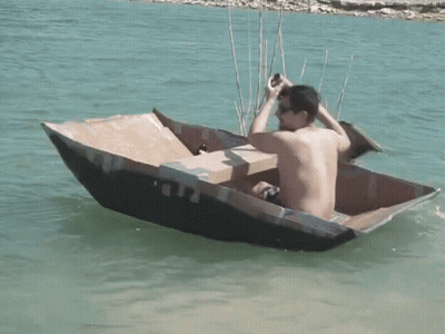 Man Sitting In Cardboard Boat With Beer GIF