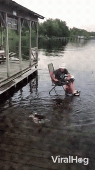 Man Sitting In Chair In Water Near Dock GIF