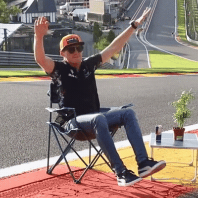 Man Sitting In Chair On Race Track With Arms Outstretched GIF