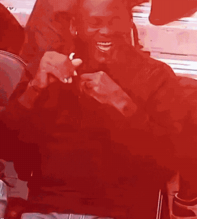 Man Sitting In Chair Smiling In Red Room GIF