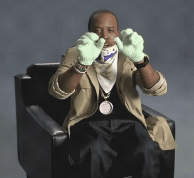 Man Sitting In Chair Wearing Green Gloves And Bo Pendant GIF