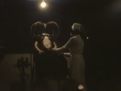 Man Sitting In Chair With Nurse In Dark Room GIF