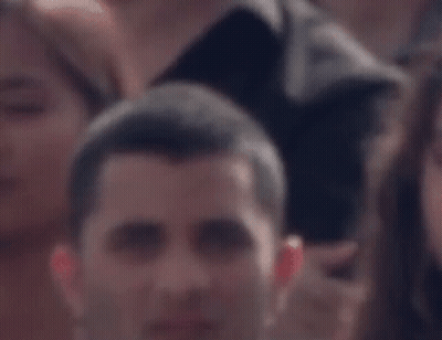 Man Sitting In Crowd Looking GIF