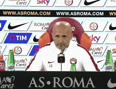 Man Sitting In Front Of As Roma Sign GIF